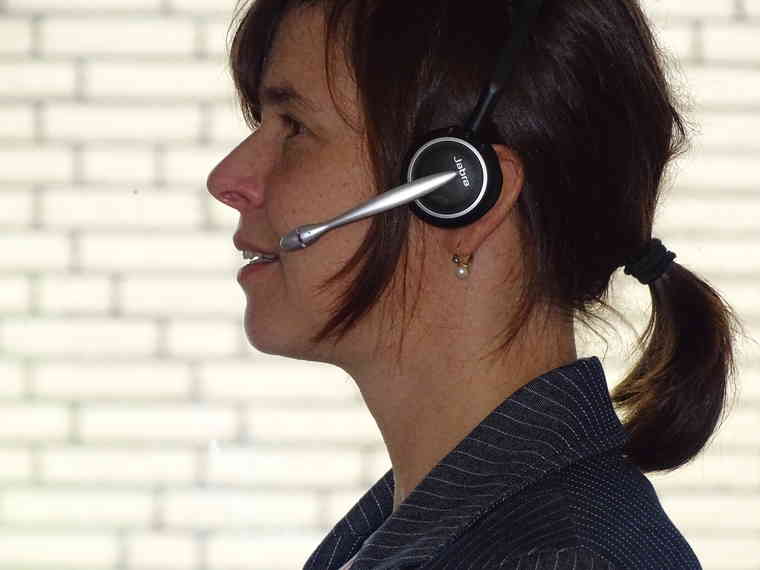 Bild zeigt eine Mitarbeiterin bei einer Telefonkonferenz