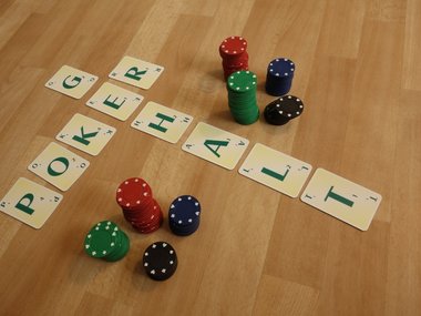 Die aus Buchstabenplätchen aneinander gelegten Worte, Poker und Gehalt, mit einigen Pokerchips.