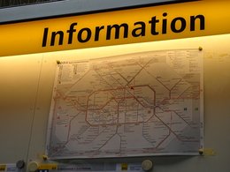 Ein gelbes Leuchtschild mit der Innschrift: Information über der Karte des Berliner U-Bahnnetzes.
