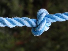 Ein blaues Seil mit einem Knoten vor verschwommenem Hintergrund.