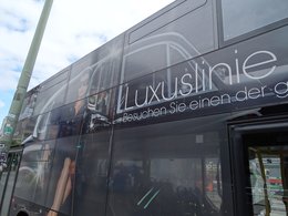 Ein schwarzer Bus mit der seitlichen Aufschrift Luxuslinie und einer glamourösen Frau.