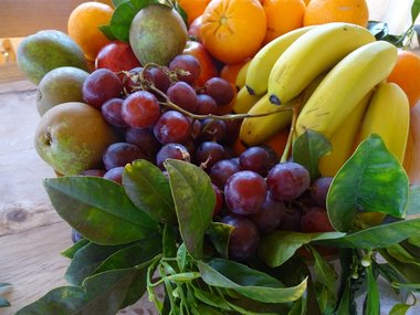 Eine Obstschale gefüllt mit Weintrauben, Apfelsinen, Äpfeln, Bananen und Birnen.