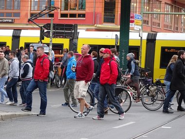 GfK-Konsumklima: Mehrere Passanten, die eine Straße überqueren vor einer Straßenbahn im Hintergrund.