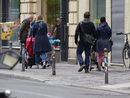 Eine Gruppe Passanten gehen auf einem Bürgersteig spazieren.