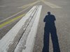Der Schatten einer Person auf einer Flughafenrollbahn.