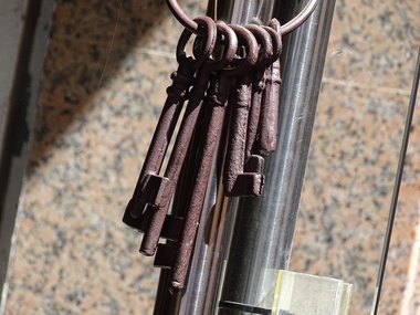 Alte Schlüssel hängen an einem Ring zusammen um ein Rohr.