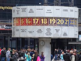 Die Berliner Weltzeituhr auf dem Alexanderplatz mit vielen Menschen darunter.