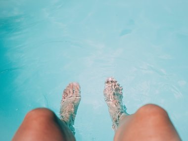 Eine Person hält seine Füße in einen Pool.