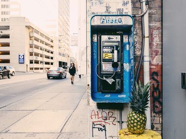 Eine Ananas in Szene gesetzt auf der Straße an einer Telefonzelle.