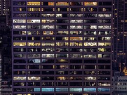 Der Einblick in zahlreiche Fenster eines riesigen Bürogebäudes bei Nacht.