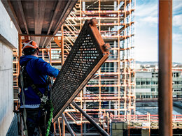 Arbeitsschutz: Das Foto zeigt einen Arbeiter auf einem Baugerüst, der einen Schutzhelm trägt.