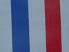 Die Fahne von Frankreich und der Ort Amilly auf einem weißen Schild an einer roten Backsteinwand.