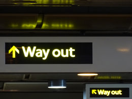 Hinweisschilder mit der Aufschrift "Way out" symbolisieren die Outplacement-Beratung.