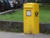 Ein großer, gelber Postkasten steht auf dem Bürgersteig.