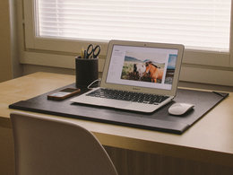 Ein aufgeräumter Büroschreibtisch mit Laptop und Handy im Home-Office.