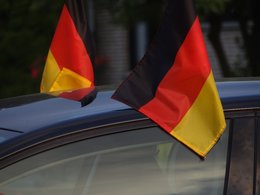 Zwei wehende Deutschlandflaggen an einem Autodach befestigt.
