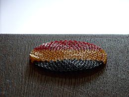 Ein Kreis aus Bügelperlen mit den Farben der Deutschlandflagge liegt auf einem Holztisch.