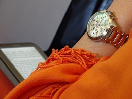 Zu sehen ist ein E-Book, eine Uhr und ein orangener Schal.
