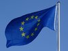 Die Flagge der Europäischen Union flattert vor blauem Himmel bei Sonnenschein im Wind.