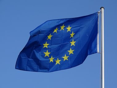 Studierenden in Europa: Die EU-Flagge vor blauem Himmel im Sonnenschein.