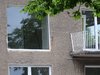 Das Bild zeigt einen Altbau mit einer grauen Putzwand, bei dem gerade die Fenster saniert wurden. Rund um die Fenster ist noch der Isolierschaum zu sehen und die unverputzten Mauerstücke.