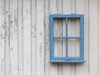 Ein blauer Fensterrahmen als Dekoration an einer weißen Wand.