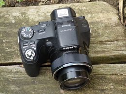 Ein Fotokamera der Marke Sony liegt auf einem Holzbalken.