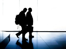 Das Bild zeigt zwei Manager bei einer Geschäftsreise an einem Flughafen.