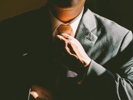 Ein Manager bzw. Mann im Anzug richtet sich seine Krawatte.