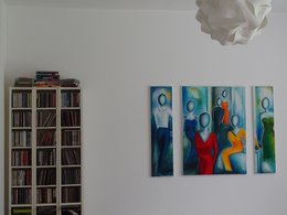 Ein dreiteiliges Bild mit abstrakten Frauen, ein Bücherregal und eine weiße Lampe in einem Raum.
