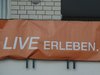 Ein orangener Banner mit den Worten: Live erleben.