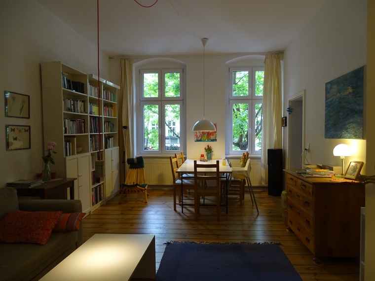 Mietwohnung: Gemütliches Wohn- und Esszimmer in einer Berliner Altbauwohnung mit Holzparkett und warmem Licht.