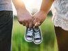 Eltern: Vater und Mutter tragen die kleinen Schuhe vom Nachwuchs zwischen sich.