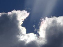 Ein Wolkenbild mit einer durchscheinenden Sonne.