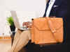 Aktentasche: Ein Geschäftsmann arbeitet an einem Notebook und hat neben sich eine Laptop-Tasche.