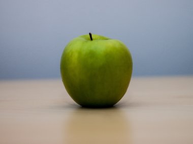 Ein grüner Apfel auf einem Tisch.