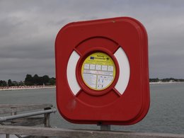 Eine rote Rettungsringstation am Meer.