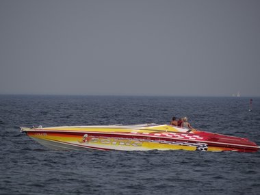 Ein luxuriöses Schnellboot mit langer Spitze in gelb und rot auf dem Meer.