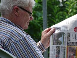 Ein Senior mit Brille liest die Tageszeitung.