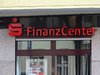 Eine Eingangstür mit dem Zeichen der Sparkasse und den Worten: Finanz Center mit roten, plastischen Buchstaben.