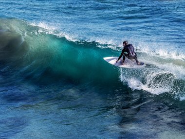 Ein Wellenreiter mit seinem Brett auf einer Welle.