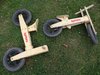 Zwei identische Holzlaufräder liegen auf einer Wiese.