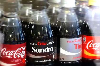 Das Bild zeigt personalisierte Flaschen von  Coca-Cola mit dem Namen Sandra und dem Namen Tim.