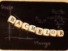 An einem Faden hängen kleine Würfel mit Buchstaben, die das Wort Bachelor ergeben und dahinter ist eine Tafel mit einer Diagrammkurve.