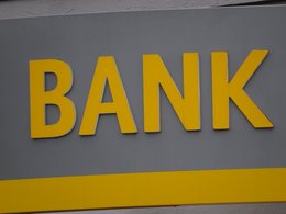 Das Wort Bank in gelb mit plastischen Buchstaben an einer Wand.