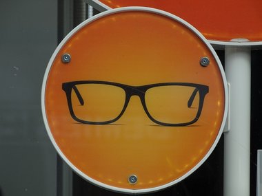 Ein rundes orangenes Schild mit einer schwarzen Brille.