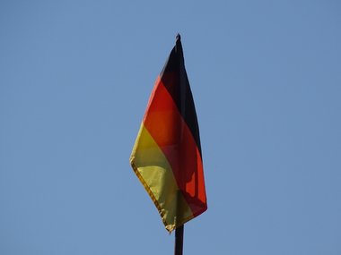 Eine Deutschlandflagge weht vor einem blauen Himmel.