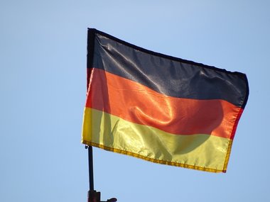Eine Deutschlandflagge weht vor einem blauen Himmel.