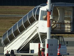 Eine fahrbare Treppe mit einer Überdachung zum Einsteigen in ein Flugzeug.