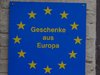 Ein blaues Schild mit den gelben europäischen Sternen und der Aufschrift: Geschenke aus Europa.